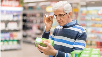 homme lisant l'étiquette d'un produit alimentaire dans les rayons d'un supermarché